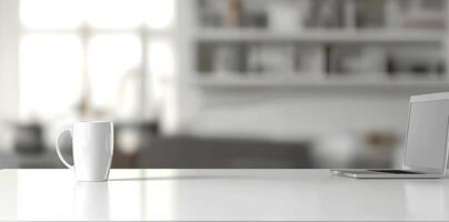 Minimalist white office desk with laptop and coffee mug on a blurred background, with space for text, representing the concept of working from home photo
