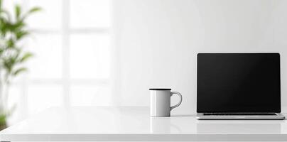 Minimalist white office desk with laptop and coffee mug on a blurred background, with space for text, representing the concept of working from home photo