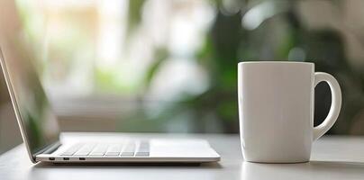 Minimalist white office desk with laptop and coffee mug on a blurred background, with space for text, representing the concept of working from home photo