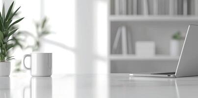 Minimalist white office desk with laptop and coffee mug on a blurred background, with space for text, representing the concept of working from home photo