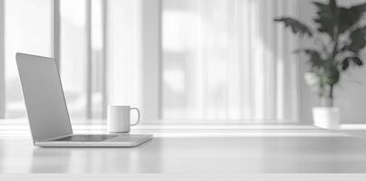 Minimalist white office desk with laptop and coffee mug on a blurred background, with space for text, representing the concept of working from home photo