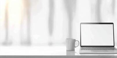 Minimalist white office desk with laptop and coffee mug on a blurred background, with space for text, representing the concept of working from home photo