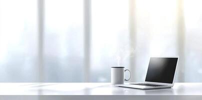 Minimalist white office desk with laptop and coffee mug on a blurred background, with space for text, representing the concept of working from home photo