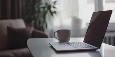 Minimalist white office desk with laptop and coffee mug on a blurred background, with space for text, representing the concept of working from home photo