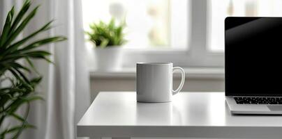 Minimalist white office desk with laptop and coffee mug on a blurred background, with space for text, representing the concept of working from home photo