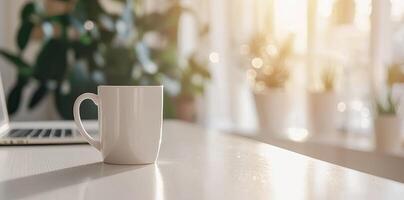 Minimalist white office desk with laptop and coffee mug on a blurred background, with space for text, representing the concept of working from home photo