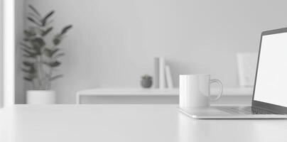 Minimalist white office desk with laptop and coffee mug on a blurred background, with space for text, representing the concept of working from home photo