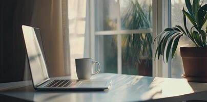Minimalist white office desk with laptop and coffee mug on a blurred background, with space for text, representing the concept of working from home photo