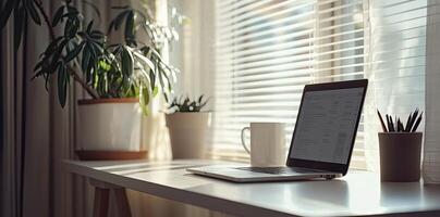 Minimalist white office desk with laptop and coffee mug on a blurred background, with space for text, representing the concept of working from home photo