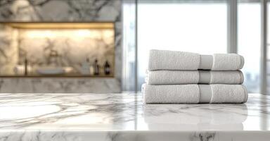 Neatly folded white towels on a marble countertop in a minimalist, luxurious bathroom with soft lighting and stylish decor photo