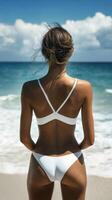 A Woman Dressed in a White Bikini Is Enjoying a Beautiful Beachfront View with Gentle Ocean Waves photo