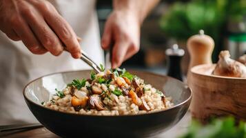 The chef prepares Risotto with mushrooms. Risotto with mushrooms is served in an elegant plate photo