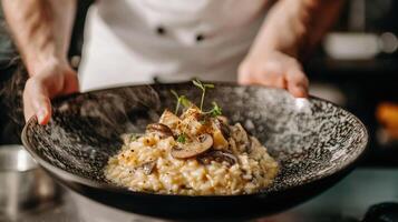 The chef prepares Risotto with mushrooms. Risotto with mushrooms is served in an elegant plate photo