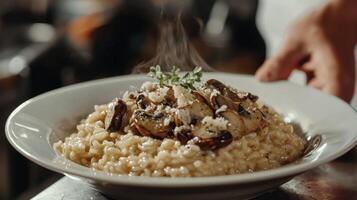 The chef prepares Risotto with mushrooms. Risotto with mushrooms is served in an elegant plate photo