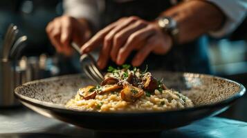 The chef prepares Risotto with mushrooms. Risotto with mushrooms is served in an elegant plate photo