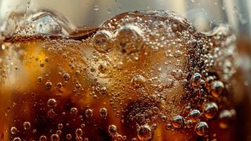 A glass of soda with ice cubes in it. The bubbles in the soda are rising to the top photo