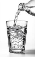 A glass of water is being poured into it. The water is clear and cold. The glass is half full photo