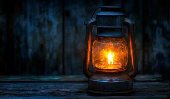A lantern with a candle inside is lit up in a dark room. The warm glow of the candle creates a cozy and inviting atmosphere. The lantern is placed on a wooden surface photo