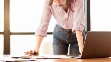 Office Work. Unrecognizable female manager standing at desk using laptop and touching tablet, copyspace photo