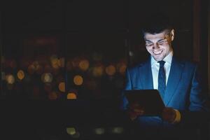 Great Business News. Happy Businessman Using Tablet Computer Browsing Internet At Work Standing In Modern Office. Copy Space photo