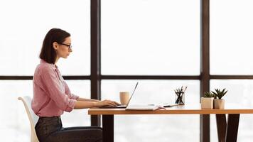 Searching Job. Focused young female worker using laptop, typing on keyboard, looking for business projects, panorama photo