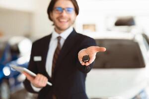 Salesperson Showing Auto Key To Camera Standing In Automobile Rental Office. Copyspace, Selective Focus photo