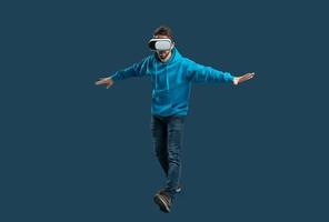 A person wearing a virtual reality headset balances on one foot, immersed in an engaging digital experience. The indoor setting highlights their focus and enthusiasm for technology. photo