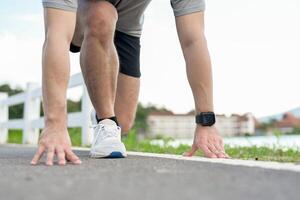 A cropped image of an active man in sportswear in a ready-to-run position, preparing to sprint. photo