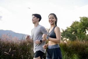Sporty Asian girl in sportswear is smiling at the camera while running with her boyfriend in a park. photo