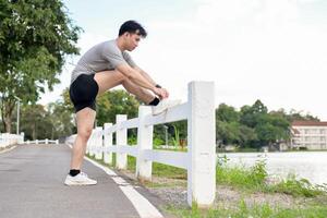 A sporty, fit Asian man in sportswear is tying his running shoelaces before running in the park. photo