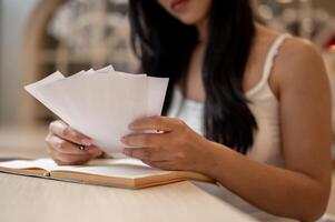 A close-up of a thoughtful Asian woman reviewing receipts in her hand, managing her expenses. photo