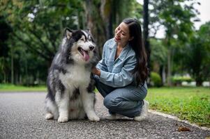 A woman is sitting and talking with her Siberian husky while taking it for a walk in the park. photo