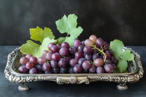 Freshly harvested purple grapes presented on a silver platter with green leaves in a rustic setting photo