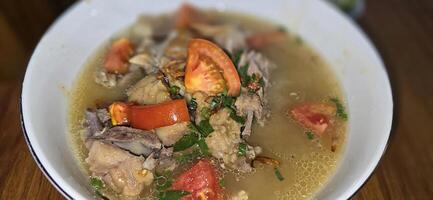 Bowl of hearty traditional lamb or mutton meat soup featuring chunks of meat and fresh vegetables, and a wedge of lime, perfect for enjoying a comforting and flavorful meal photo