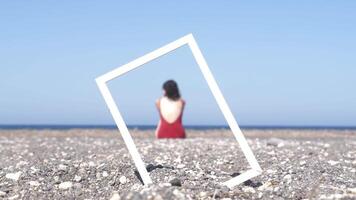 Woman Sitting In The Beach On A Hot Summer Day Seen Through A Portrait Frame video