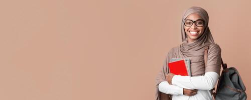 Education Concept. Portrait Of Smiling Black Muslim Girl In Hijab With Backpack And Notepads Posing Over Yellow Background With Empty Space photo