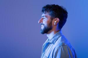 A man with a beard is shown wearing ear buds, likely listening to music or a podcast. He appears focused and engaged with his audio device. photo