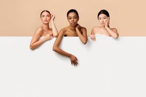 Multiracial Beauty. Three Mixed Women Posing Standing Behind White Board For Text Posing Over Gray Studio Background. Copy Space photo