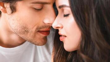A close-up shot of a young man and woman about to kiss. They are looking at each other with love and affection, their noses touching, their eyes closed photo