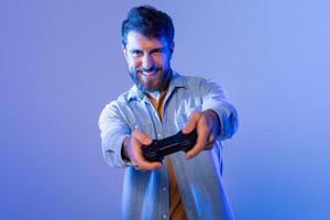 A man is seen holding a game controller in his hands, focusing intently on the screen as he plays. The controller is black in color with various buttons and joysticks. photo