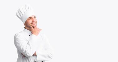 Happy Chef Man Thinking And Dreaming About Own Restaurant Posing Touching Chin Over White Background. Studio Shot, Empty Space photo
