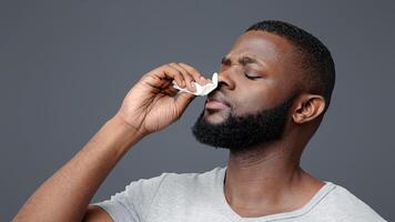 Afro guy touching his nose with napkin, bleeding or having runny nose, free space photo