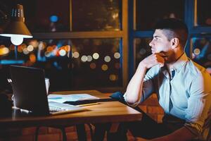 Business Career Concept. Thoughtful Guy Sitting At Work At Night Thinking On Business Project In Modern Office. Copy Space photo