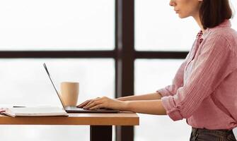 Working On Project Concept. Side view close up of young business woman's hands using laptop at modern office photo