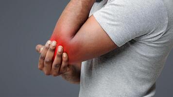 Cropped of black man rubbing his injured highlighted with red elbow, side view, copy space photo