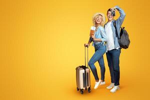 Ready for vacation. Happy couple with suitcase and tickets over yellow background, copy space photo