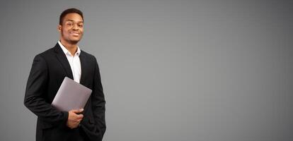 Confident Businessman. Black guy holding laptop looking at camera, isolated over white background, panorama, copyspace photo