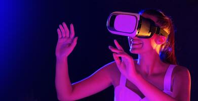 A woman wearing a virtual reality headset, exploring a digital environment while immersed in the virtual experience in dusk. She is interacting with the technology photo