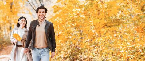 Excited guy showing his pretty girlfriend beautiful autumn forest, pulling her hand, copy space photo