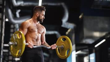 Handsome naked weightlifter lifting heavy barbell in gym, free space photo